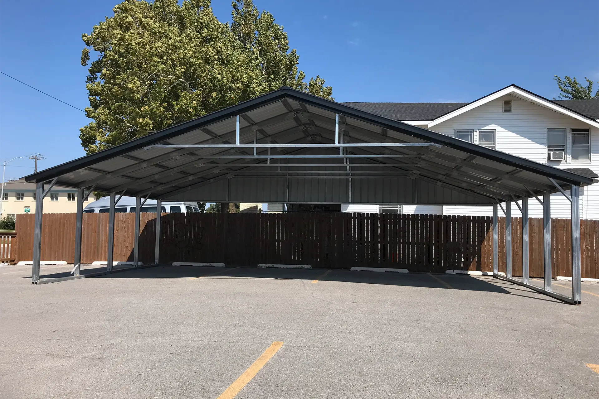 Black metal 3 car carport with vertical roof panels and open sides.